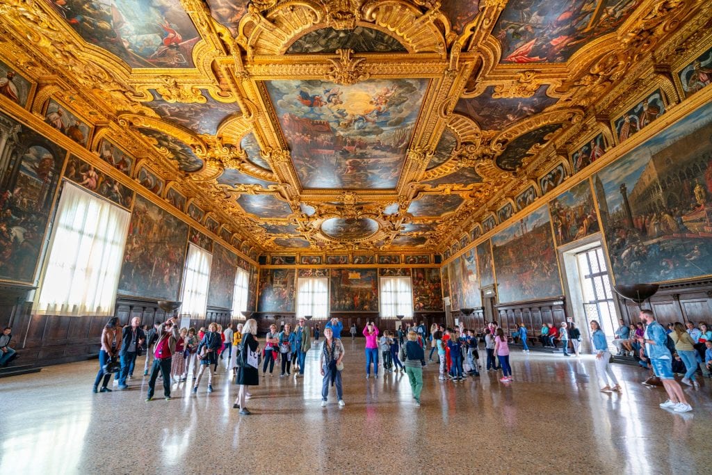 总督宫最大的议事厅的内部照片——在威尼斯的一天里绝对值得一去!天花板是镜头的焦点，上面覆盖着金色，远处有一群人。