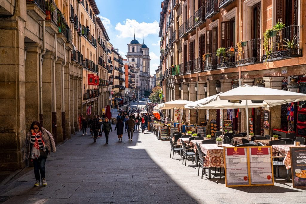 西班牙马德里一条安静的街道的照片，桌子的右边有伞。