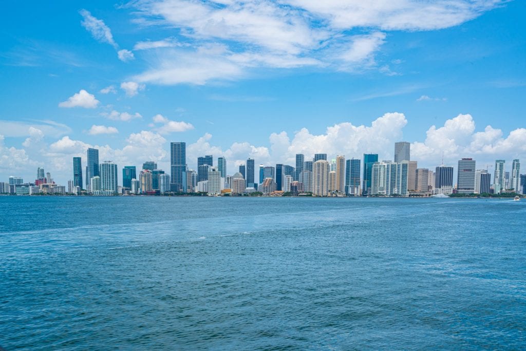 从海湾对面看到的迈阿密市中心的天际线。照片的中央是天际线，下面是水，上面是蓝天。