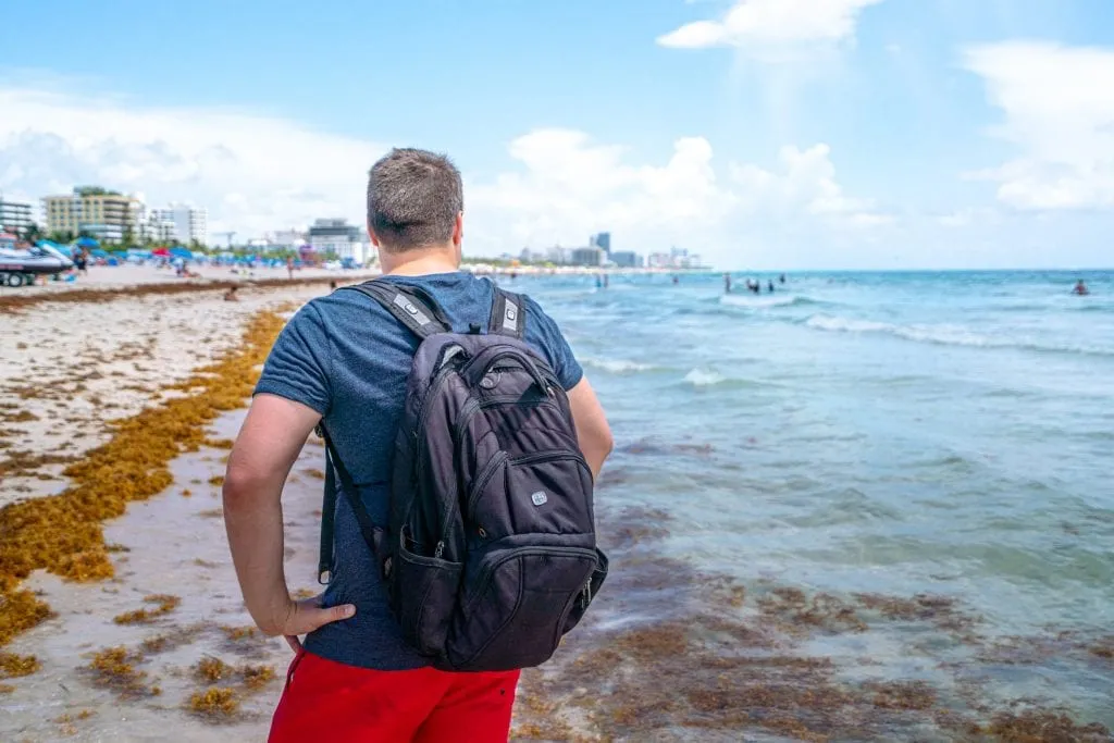 杰里米背对着镜头站在南海滩。他背着一个黑色的背包。
