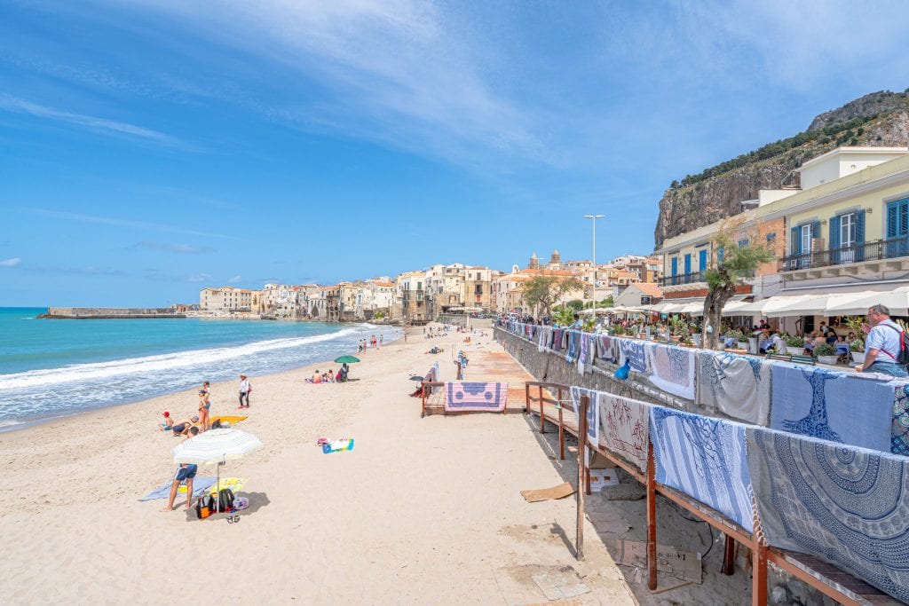 意大利西西里岛的Cefalu海滩，右边有毛巾出售，左边可以看到大海，是西西里岛旅行的最佳去处之一必威体育官方登录