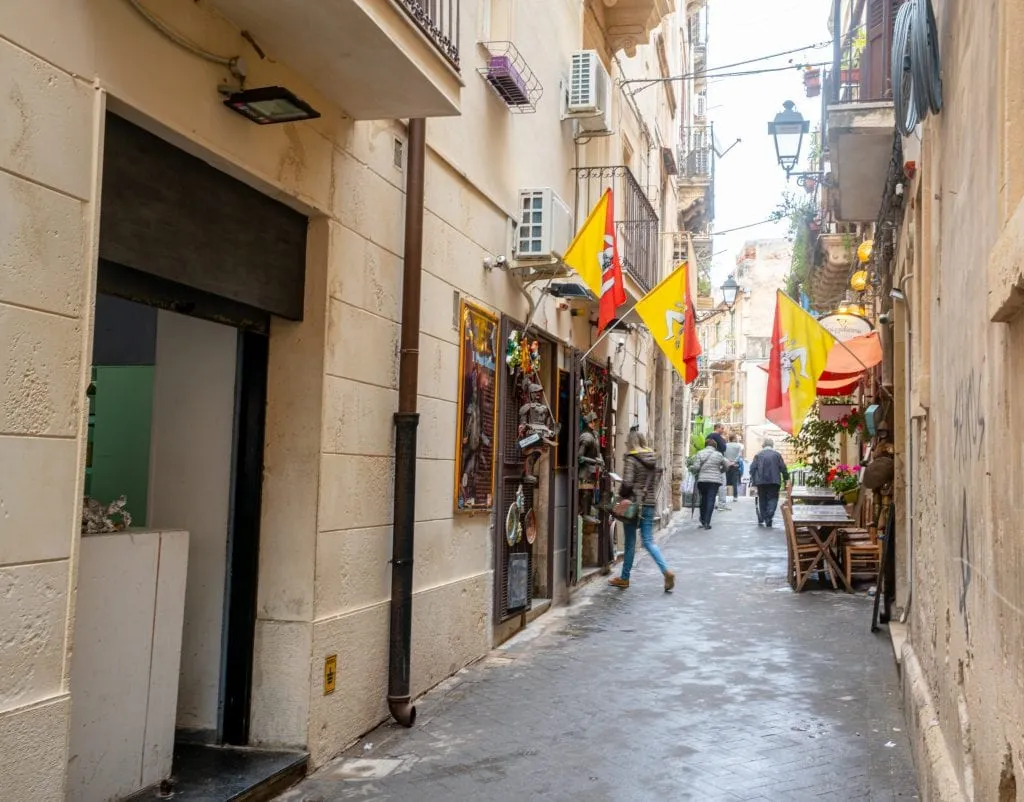 西西里岛锡拉库扎的一条小街上，商店橱窗外挂着旗帜
