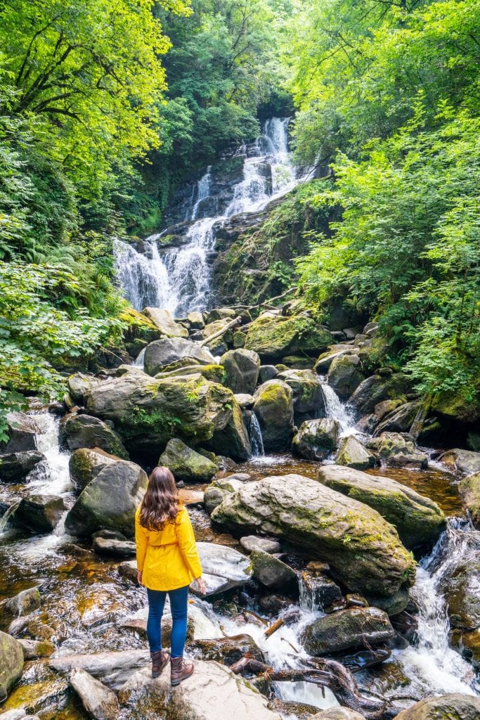 身着黄色雨衣的凯特·斯道姆站在爱尔兰基拉尼国家公园的托克瀑布前