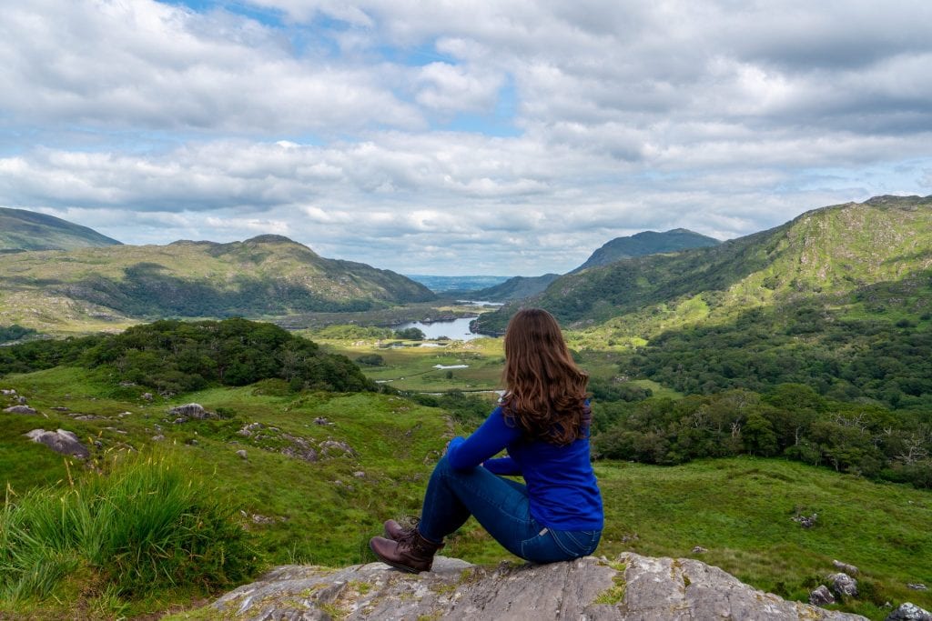 凯特·斯道姆身着蓝色长袖衬衫，俯瞰着基拉尼国家公园——爱尔兰之旅的必看景点!
