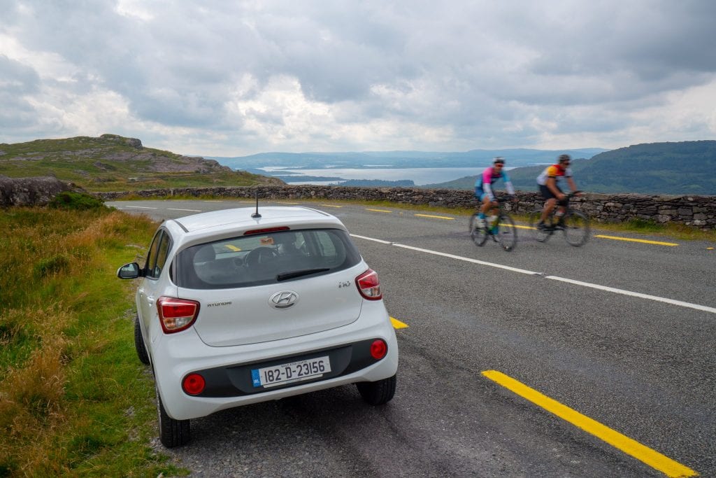 在爱尔兰自驾游期间，汽车停在路边的照片。照片右侧可以看到两个骑自行车的人经过。