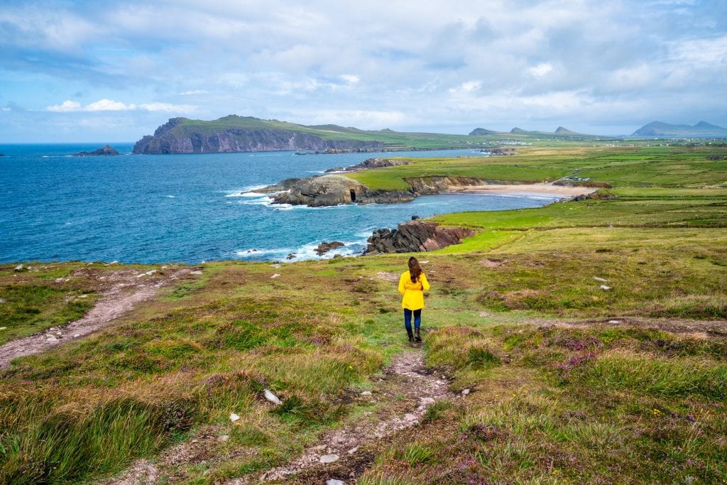 凯特·斯道姆在爱尔兰丁格尔半岛的Slea Head车道上，背对着镜头，穿着一件黄色雨衣。