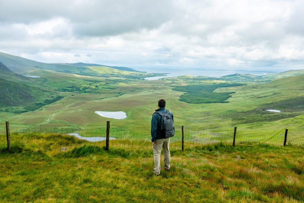 杰里米·斯托姆背着一个安全背包，穿着一件灰色夹克，俯瞰爱尔兰康纳山口