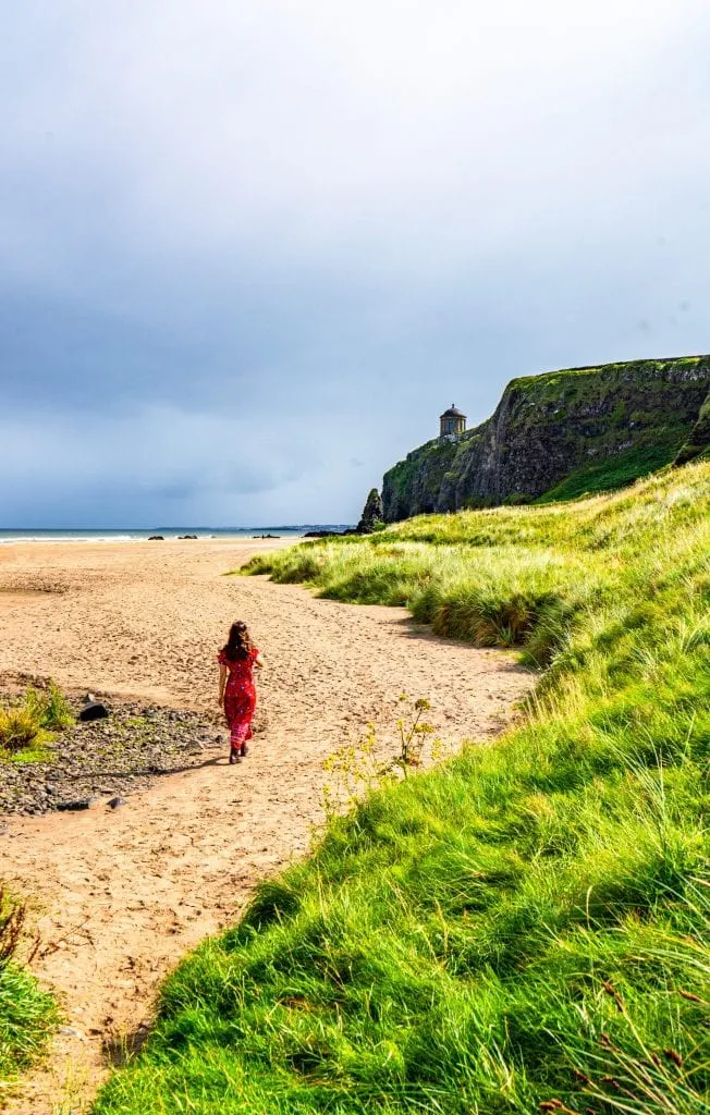 凯特·斯道姆在北爱尔兰的下坡海滩上穿着红色连衣裙，这是爱尔兰最值得一看的风景之一