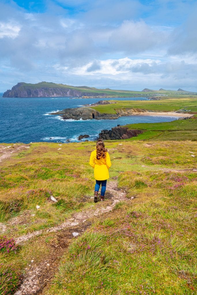 凯特·斯道姆身着黄色雨衣在爱尔兰邓莫尔角拍摄，背景中可见三姐妹