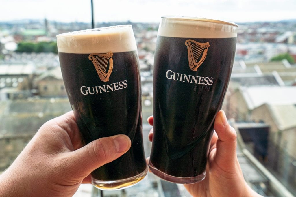 两品脱的吉尼斯黑啤酒举在吉尼斯仓库的窗户前——在爱尔兰都柏林的两天里，一定要去看看这个地方。