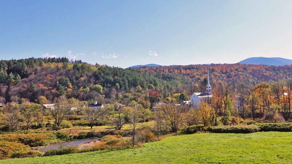 从上面看佛蒙特州的斯托，树上有秋天的颜色，照片右侧是白色的教堂