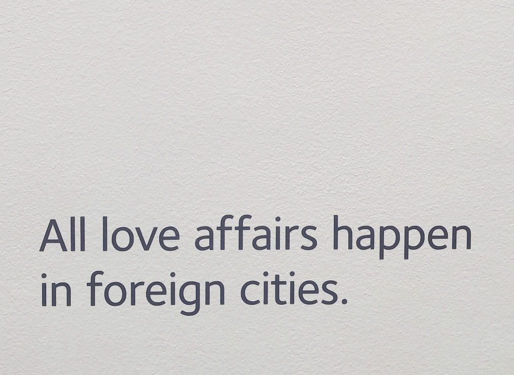 克罗地亚萨格勒布失恋博物馆的白墙照片。黑色的文字写着“所有的爱情都发生在外国的城市。”