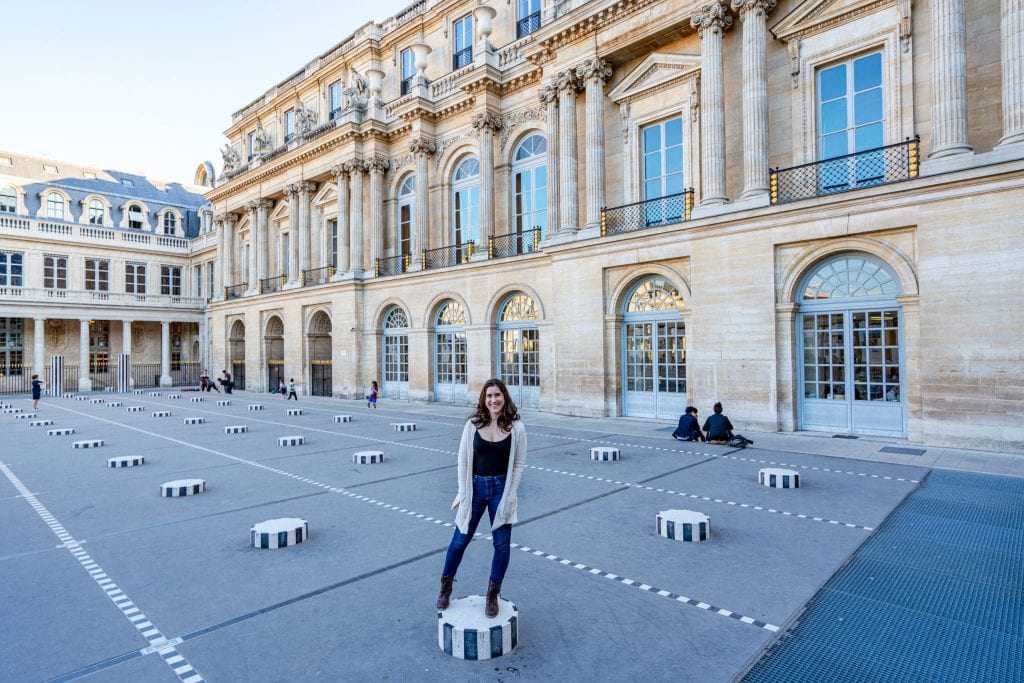 凯特·斯道姆身穿黑色衬衫和奶油色开衫，站在法国巴黎的一个布伦广场上——如果你喜欢古怪的拍照，一定要来这里，作为你周末巴黎之旅的一部分!