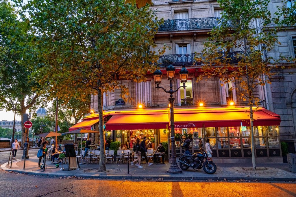 舒适的路边小酒馆在巴黎的一个晚上，室外的桌子被灯照亮