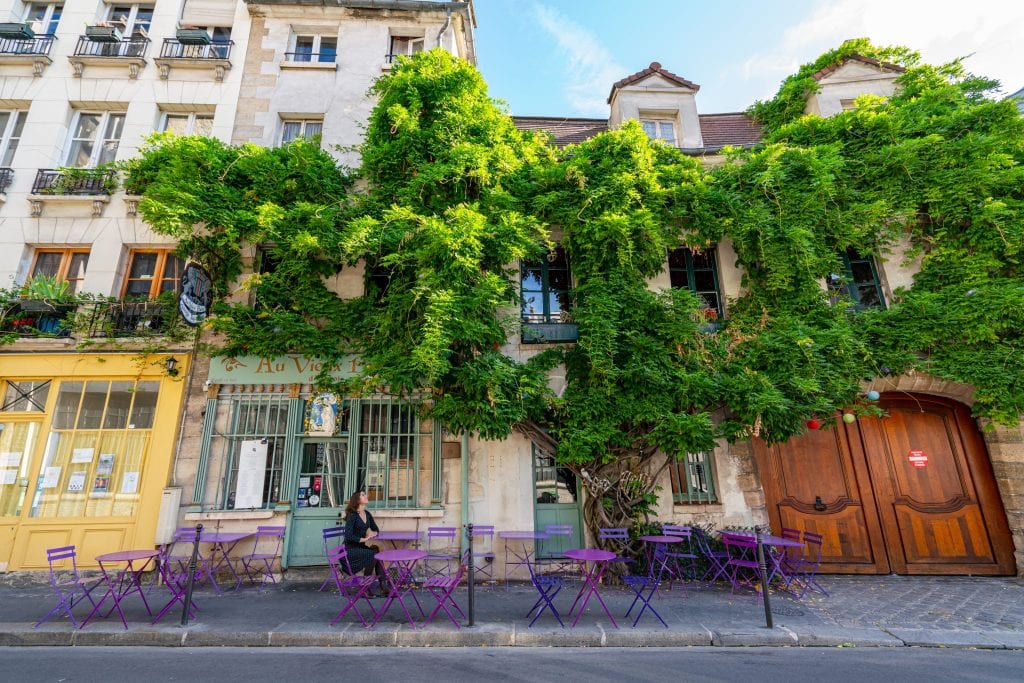 凯特·斯道姆身穿灰色连衣裙坐在Cafe Au Vieux前，这是巴黎最具ins魅力的场所之一