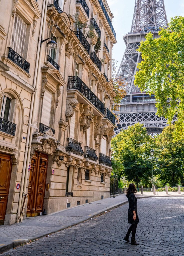 凯特·斯道姆身着灰色连衣裙站在巴黎大学街，身后是埃菲尔铁塔