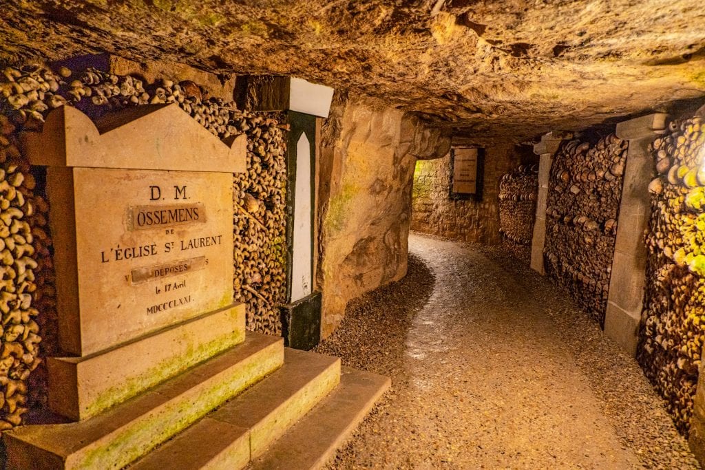 Interior of the catacombs in Paris with a gravestone on the left side of the photo