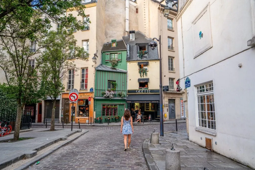 凯特·斯道姆穿着蓝白相间的裙子站在奥黛特咖啡馆前——在巴黎的一天，你可以考虑在这里喝咖啡!