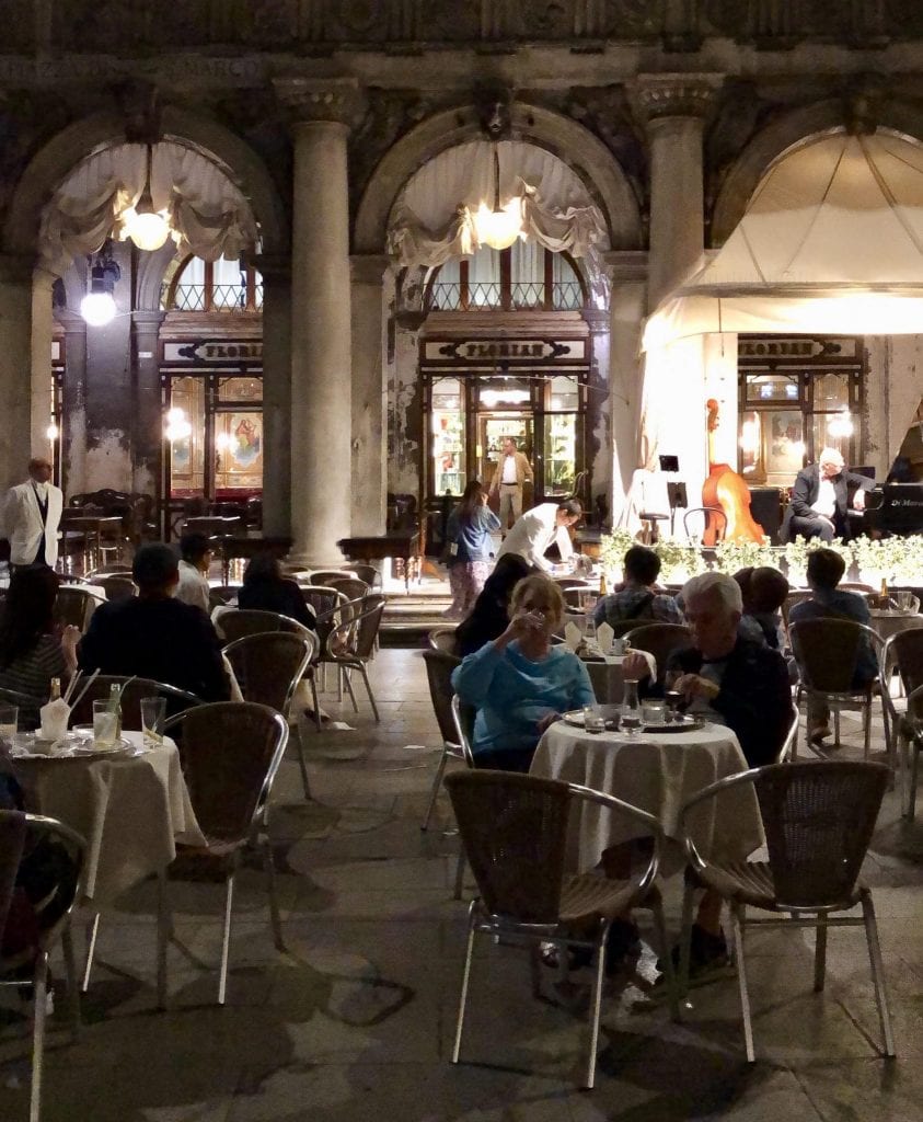 晚上的弗洛里安咖啡馆，顾客们坐在咖啡馆前面的桌子上。