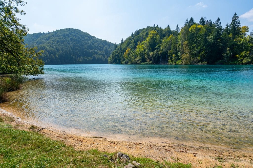 克罗地亚Plitvice湖泊国家公园的小海滩，绿松石色的湖泊占据了大部分的框架