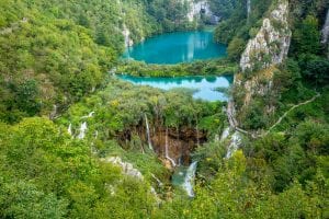 从上方俯瞰克罗地亚Plitvice湖国家公园的明信片，中心的湖泊被树木环绕，是克罗地亚10天之旅的必看景点!