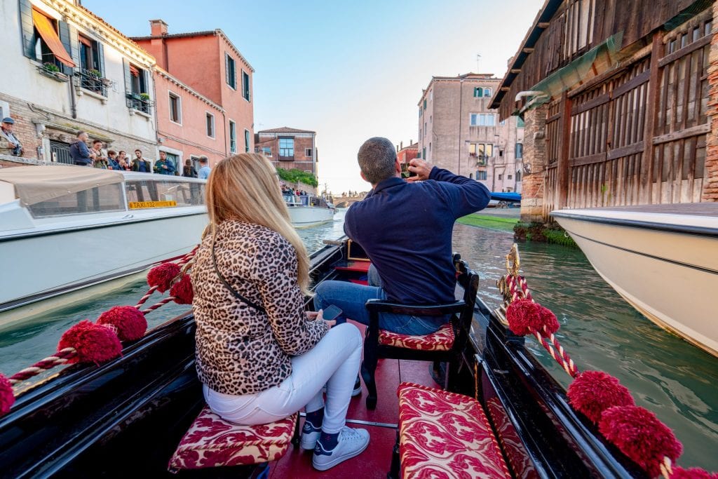 一个男人和一个女人在威尼斯乘坐贡多拉，男人正在拍照