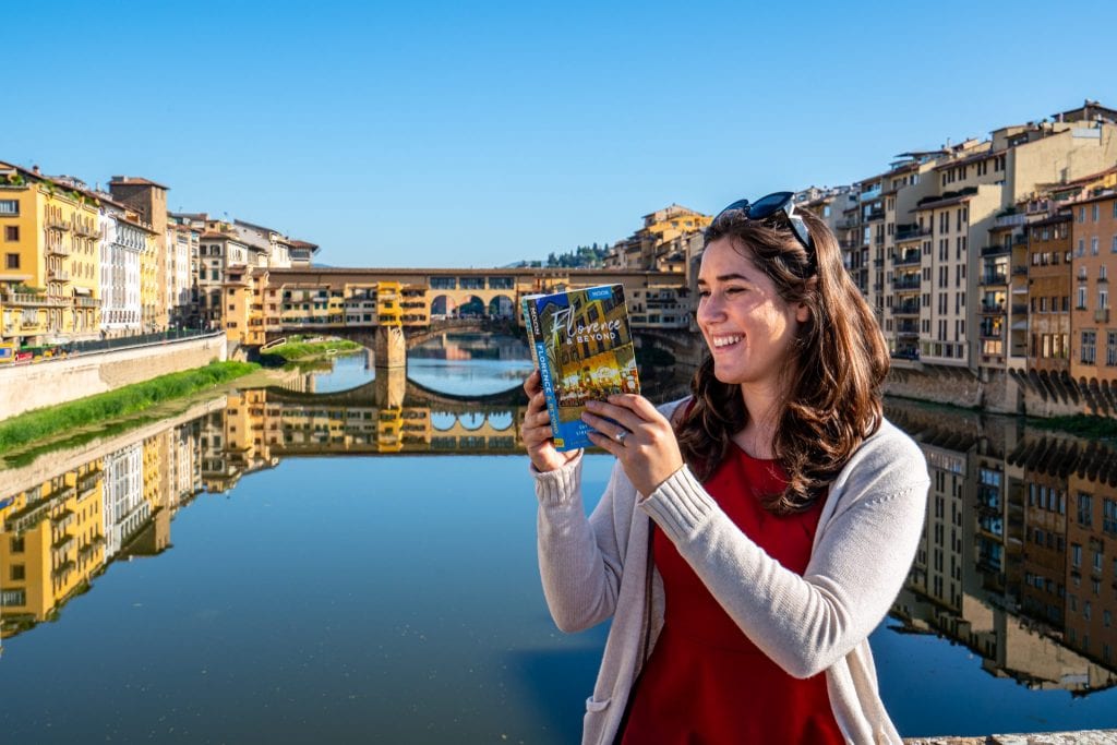 凯特·斯托姆阅读《月亮佛罗伦萨与超越》的照片，背景是阿诺河和维奇奥桥
