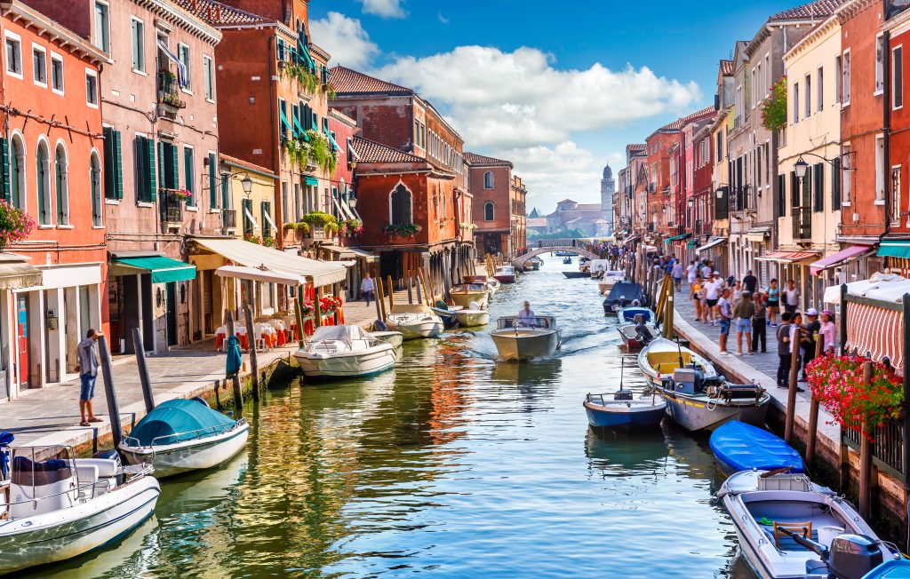 在意大利穆拉诺，一条繁忙的运河旁排列着五颜六色的建筑