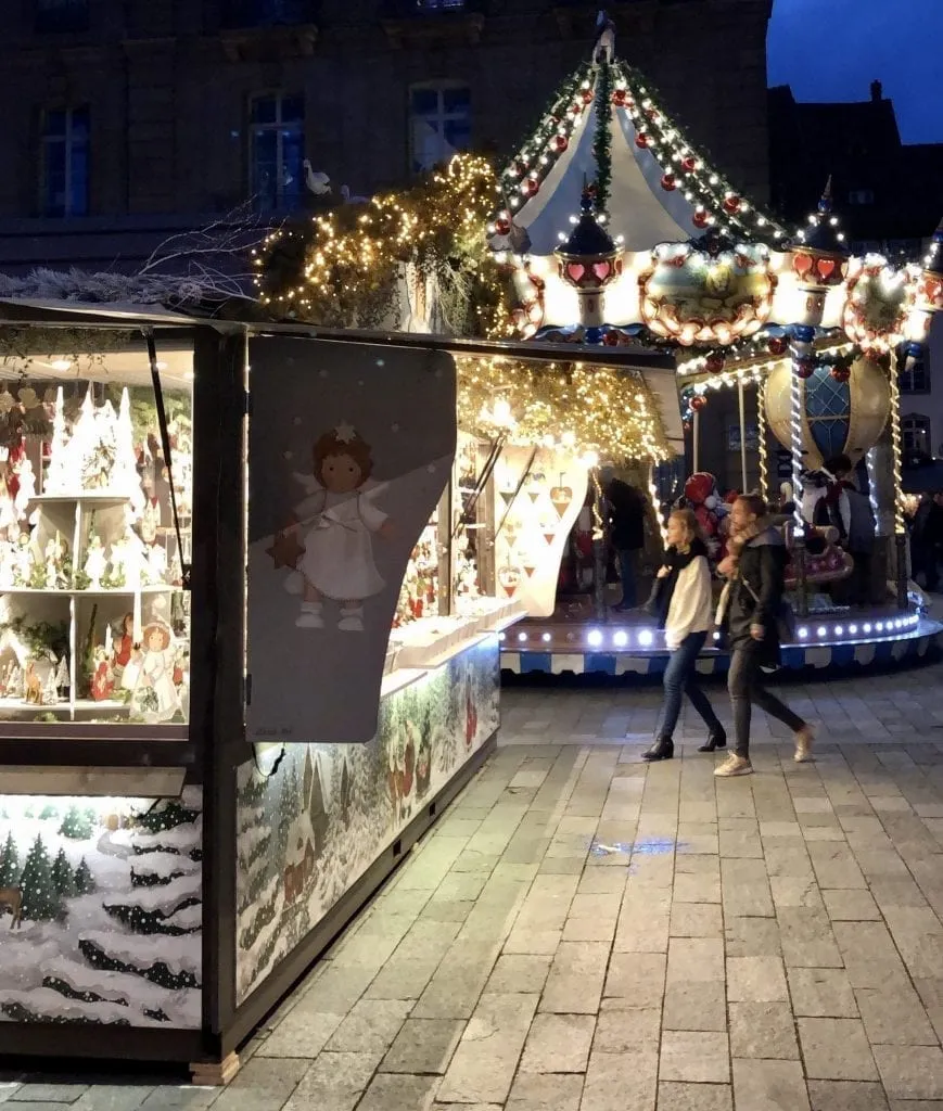 12月，在斯特拉斯堡，圣诞市场上有旋转木马的摊位和一对夫妇在夜晚散步