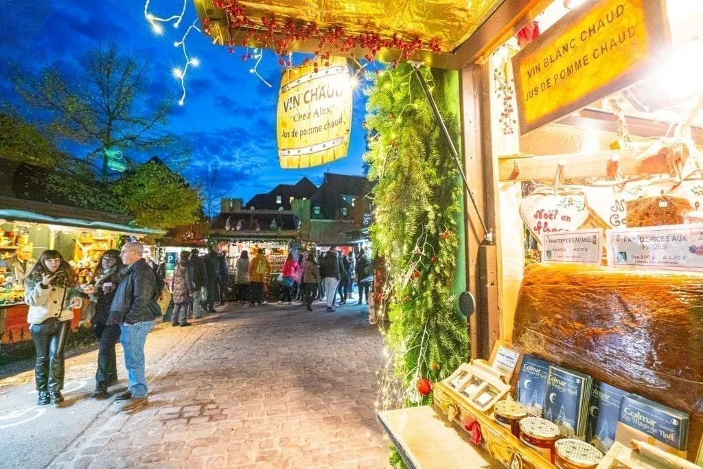 科尔马的圣诞市场摊位在夜晚开放，背景中可见深蓝色的天空