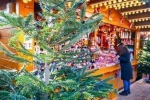 近距离的圣诞市场摊位后面的树和购物的人，一个典型的观点在圣诞节在欧洲的行程