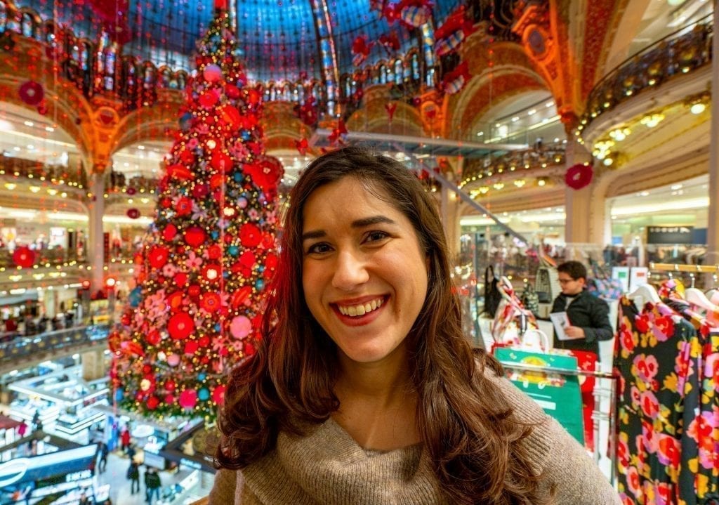 凯特·斯道姆身穿棕色毛衣，站在2019年巴黎老佛爷百货圣诞树前
