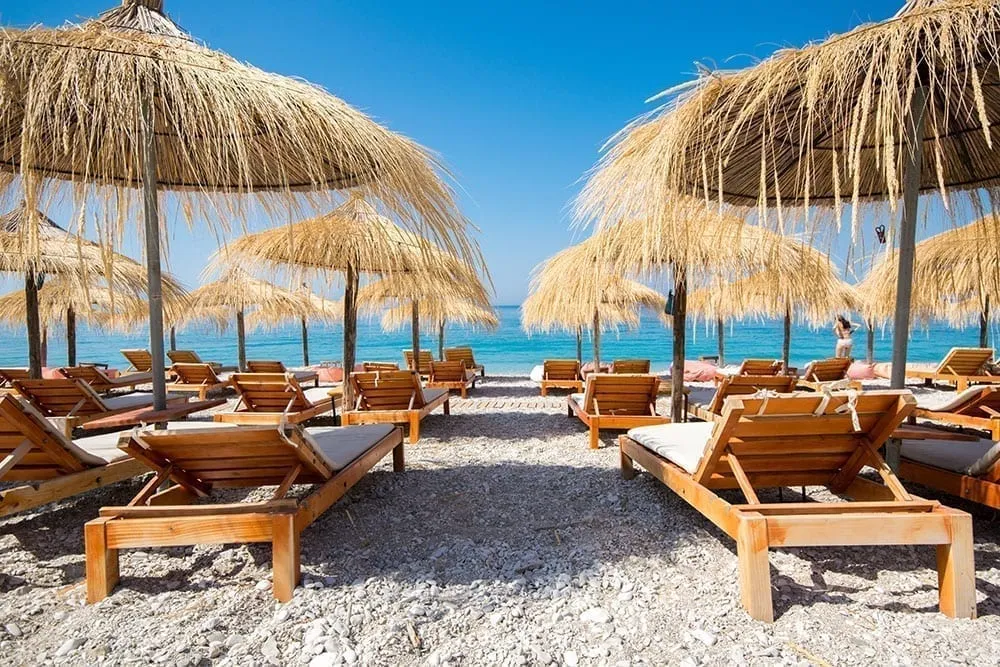 沙滩椅和雨伞正对着阿尔巴尼亚里维埃拉明亮的大海，这被视为欧洲自驾游行程的一部分