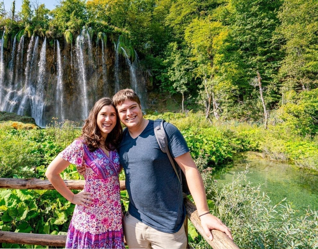 Kate Storm and Jeremy Storm standing in front of a waterfall when visiting Plitvice Lakes National Park Croatia