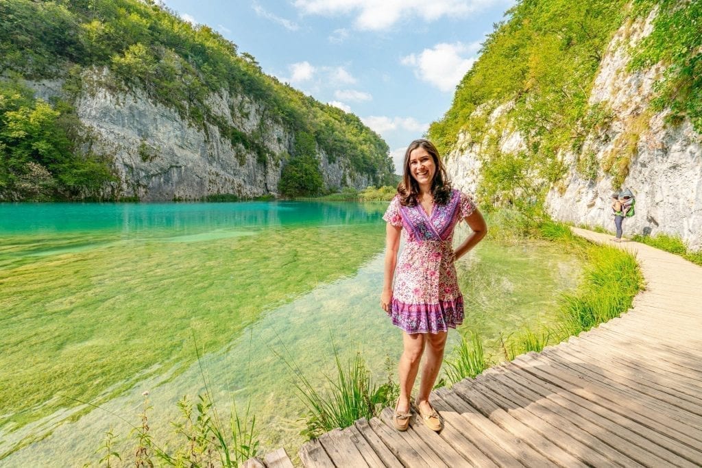 凯特·斯道姆在普利特维采湖度假时，穿着粉色连衣裙站在湖上的木板路上