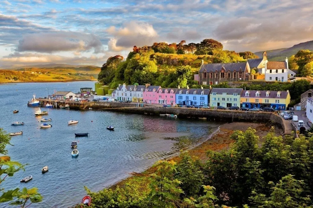 色彩斑斓的村庄坐落在苏格兰的斯凯岛上的水面上，船停在港口——苏格兰是欧洲最好的自驾游选择的家园!
