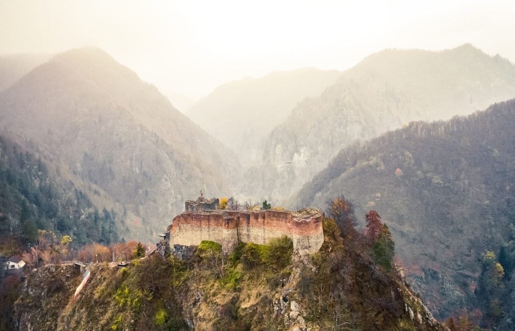 黄金时段罗马尼亚Poenari城堡的鸟瞰图，背景是群山