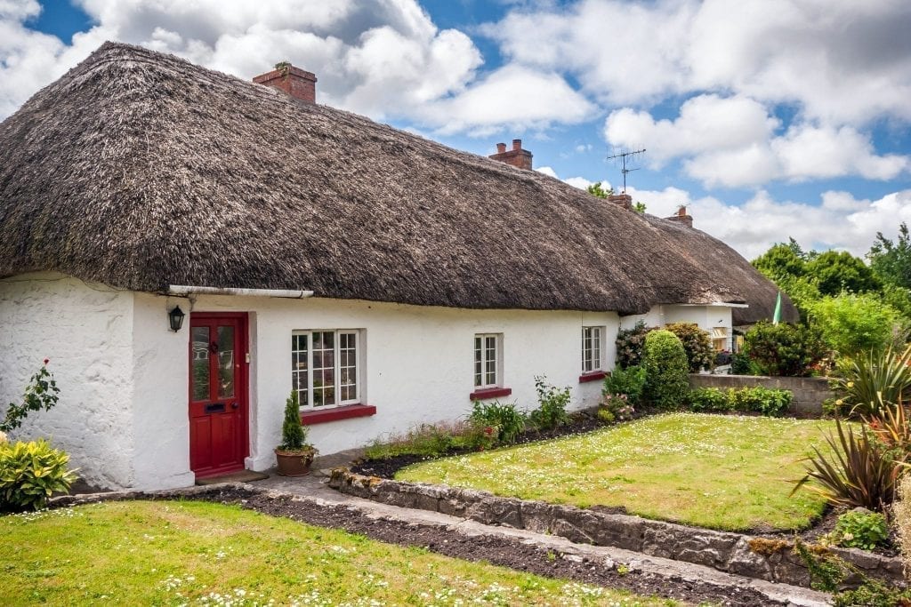 爱尔兰阿代尔的茅草屋顶小屋，白墙红门。阿代尔是爱尔兰最好的小镇之一