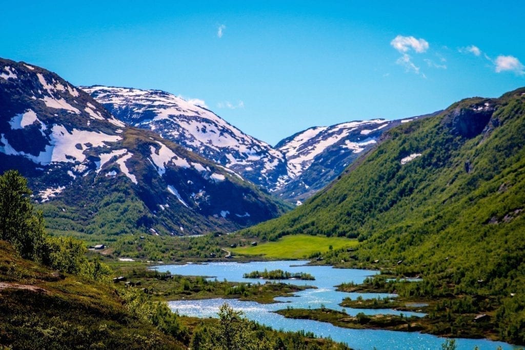 挪威明亮的蓝色峡湾，背景是白雪皑皑的群山