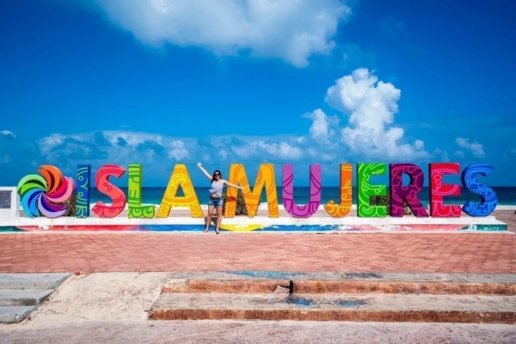 凯特·斯托姆站在五彩缤纷的Isla Mujeres标志前，这是墨西哥Isla Mujeres的一个有趣的地方