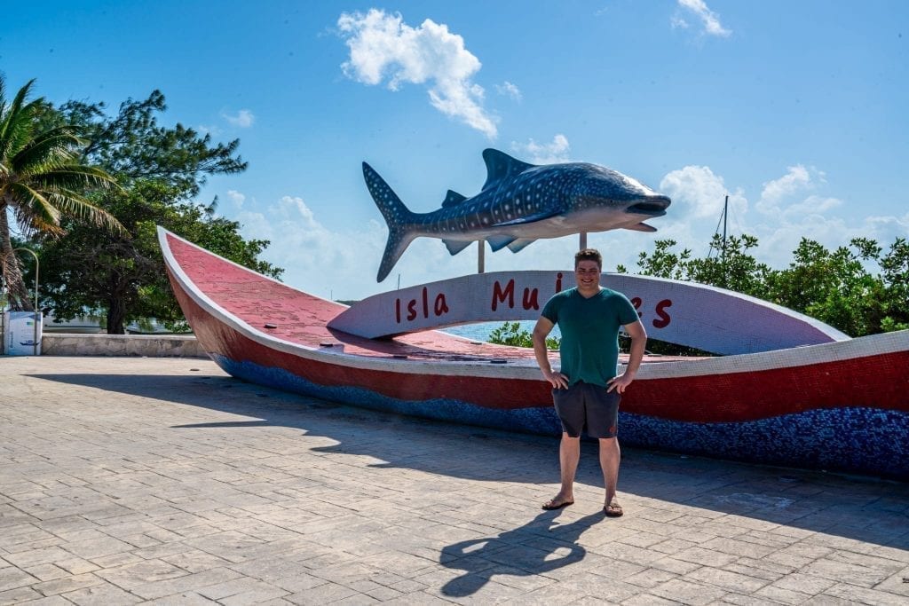 杰里米·斯托姆站在Isla Mujeres招牌前，上面有一条鲸鲨