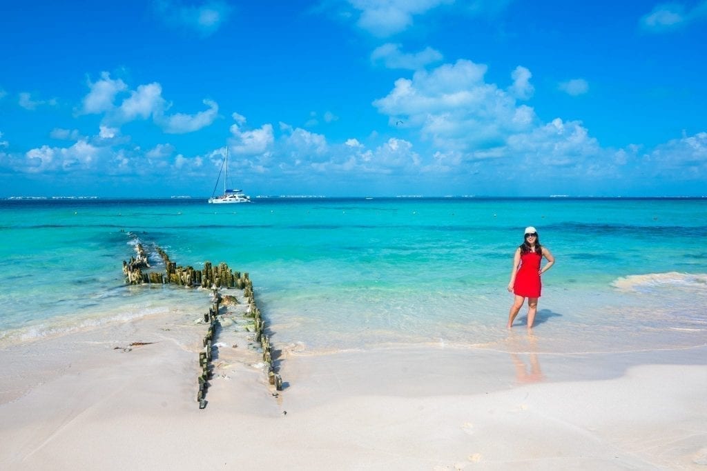 身着红裙的凯特·斯道姆站在女人岛的北海滩上。左边是码头的残骸。