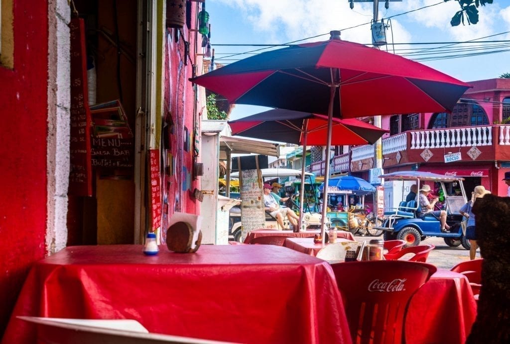 墨西哥的户外餐厅，红色桌布和红色雨伞遮挡着桌子