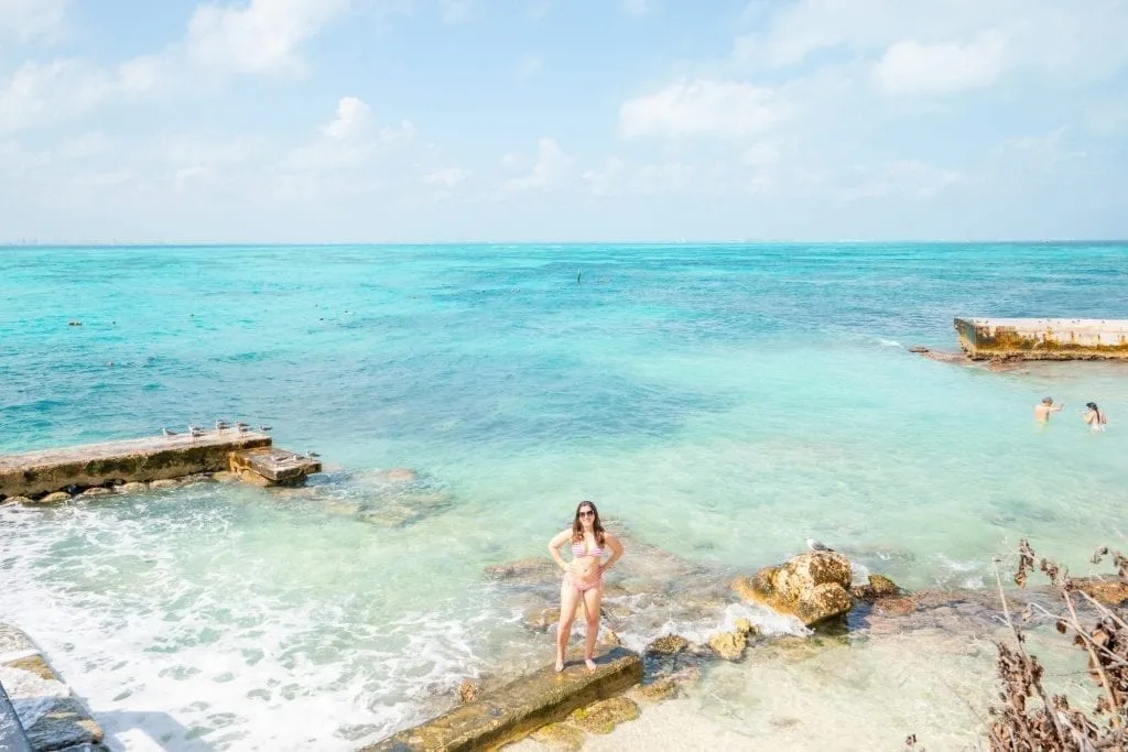 凯特·斯道姆站在加拉冯·德·卡斯蒂亚的礁石上，绿松石般的海水环绕着她