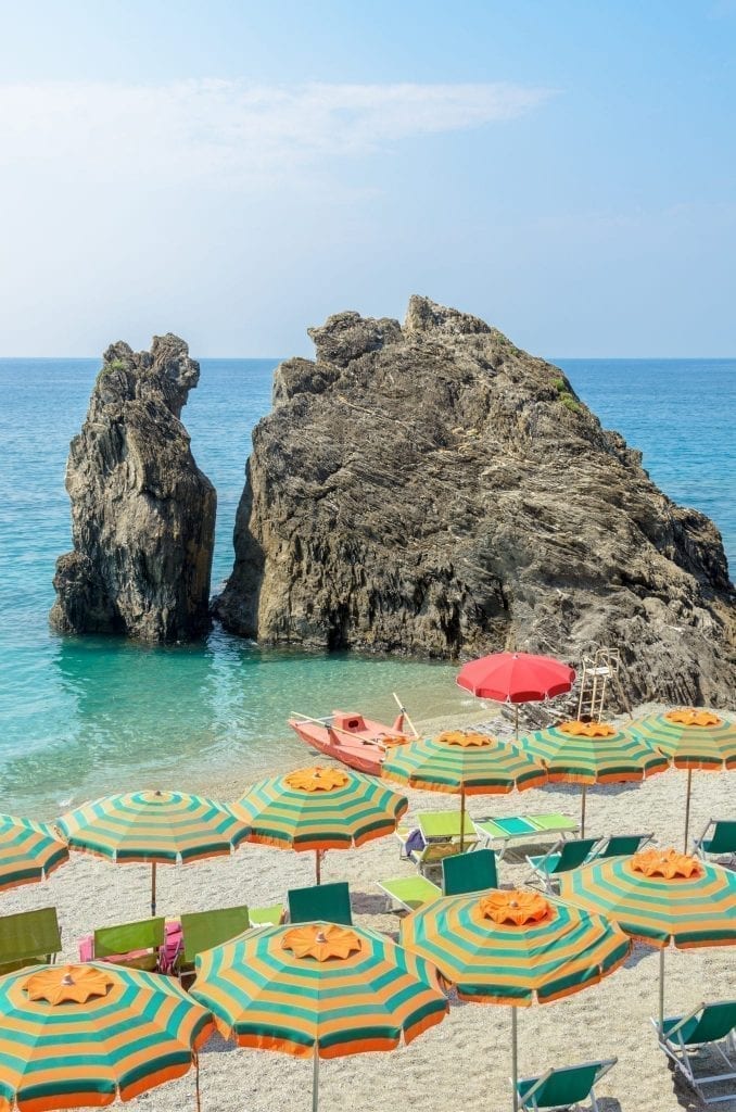 View of Spiaggia di Fegina in Monterosso al Mare with colorful umbrellas in the foreground, one of the best photography locations in Cinque Terre Italy