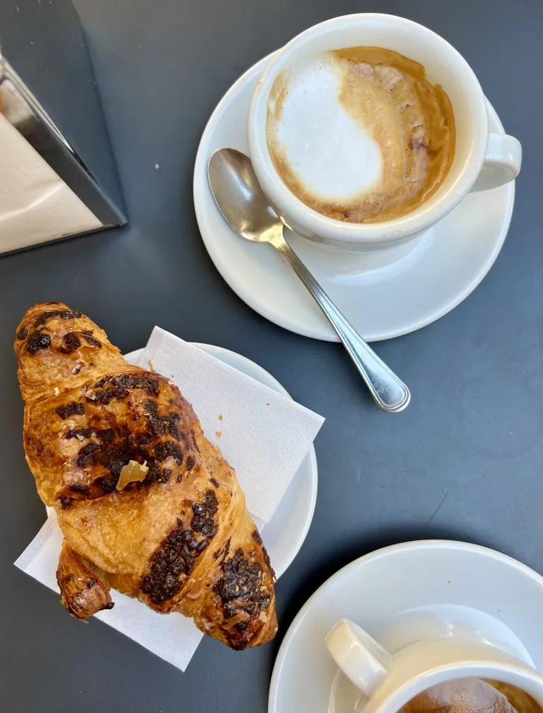 图为意大利咖啡吧桌上的咖啡和羊角面包