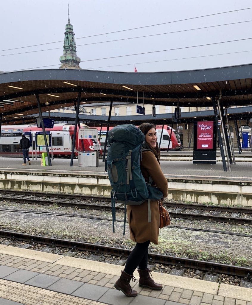 Kate Storm waiting for a train on a platform in Luxembourg, as part of a travel Europe by train adventure across Europe