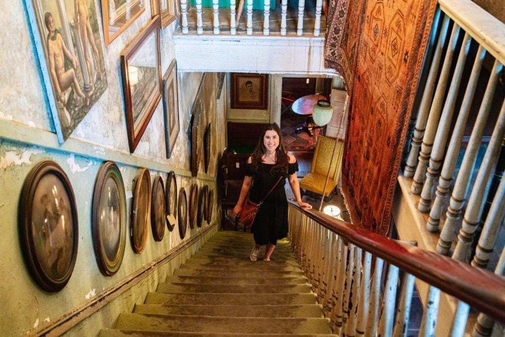 在佐治亚州萨凡纳的一个漫长周末，凯特·斯道姆身穿黑色连衣裙站在亚历克斯·拉斯金古董店的楼梯上