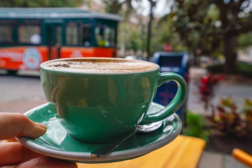 在萨凡纳手推车前，一个绿色杯子里盛着五香薰衣草摩卡。咖啡来自柯林斯区，萨凡纳最好的摄影地点之一