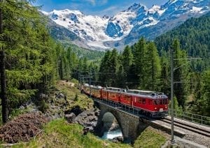 红色火车穿过瑞士，背景是清晰可见的山脉——这样的景色是乘坐火车去欧洲旅行的最佳理由之一必威体育官方登录